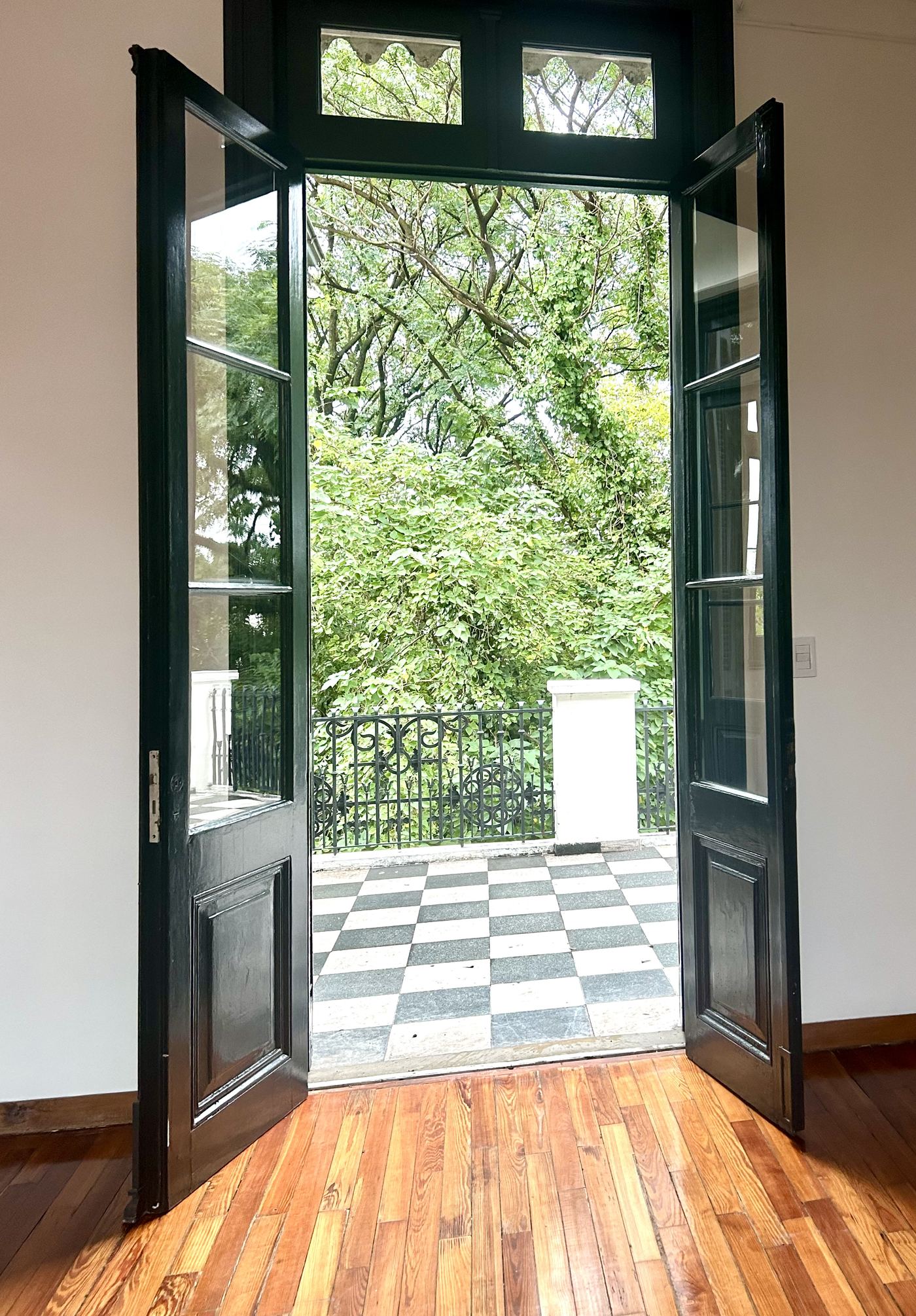 Puerta balcón abierta hacia el jardín, con piso de madera