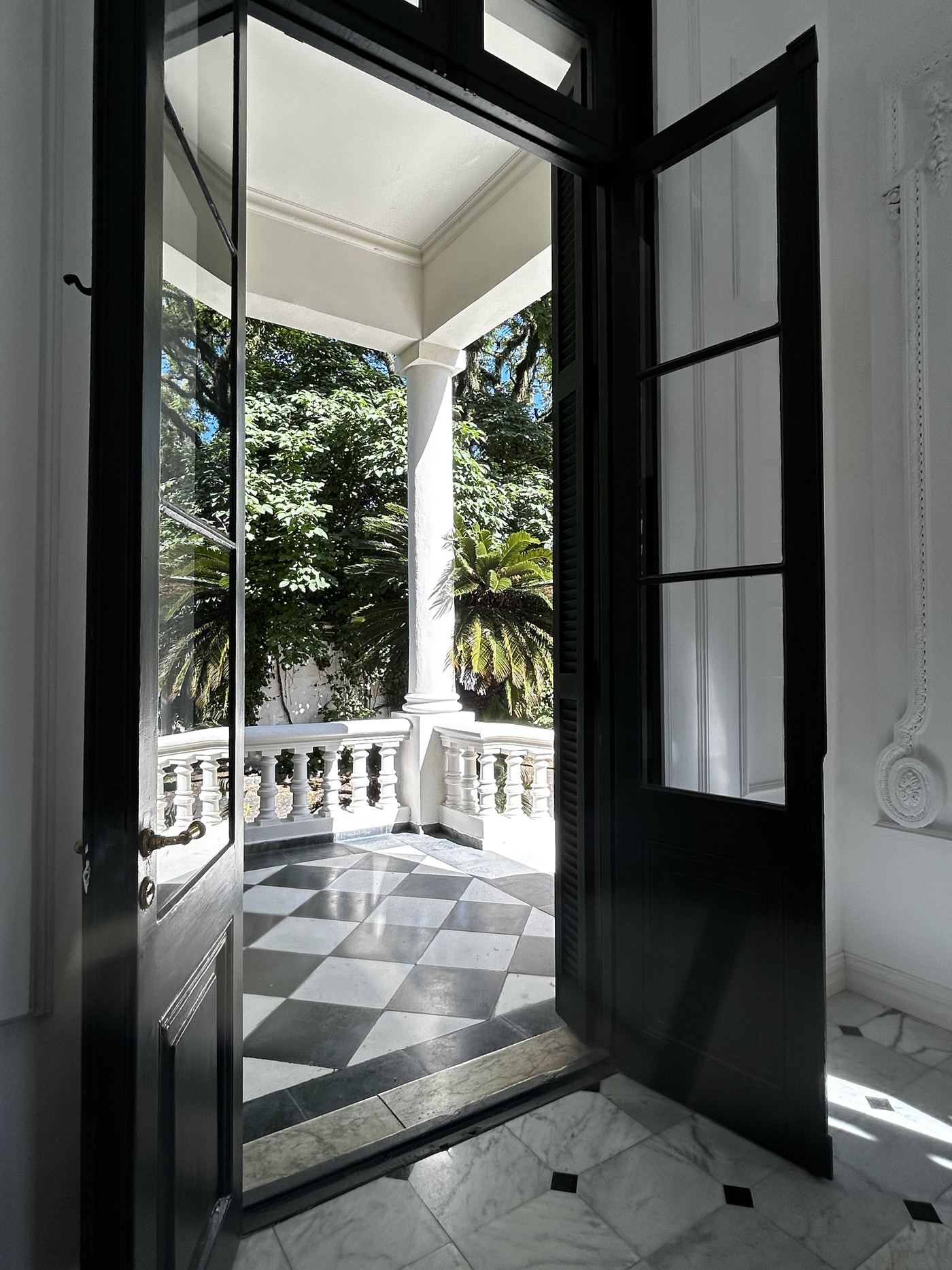 Entrada con puerta hacia balcón de columnas y piso de mármol